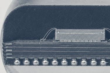 A polished cross-section through a packaged integrated circuit, showing the moulding compound, the silicon die with its bond wires, the layered substrate beneath it and a row of solder balls along the bottom.